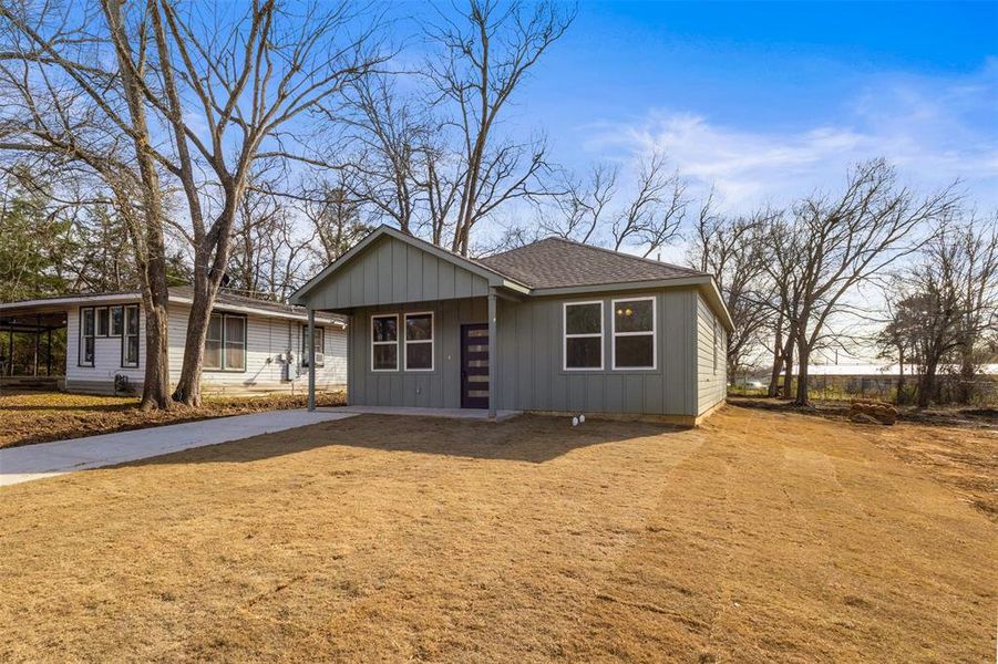 Ranch-style house with roof with shingles, a front yard, and board and batten siding
