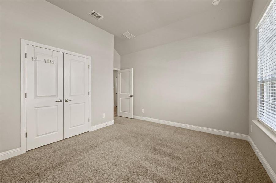 Secondary bedroom with double-door closet and clean, neutral design.