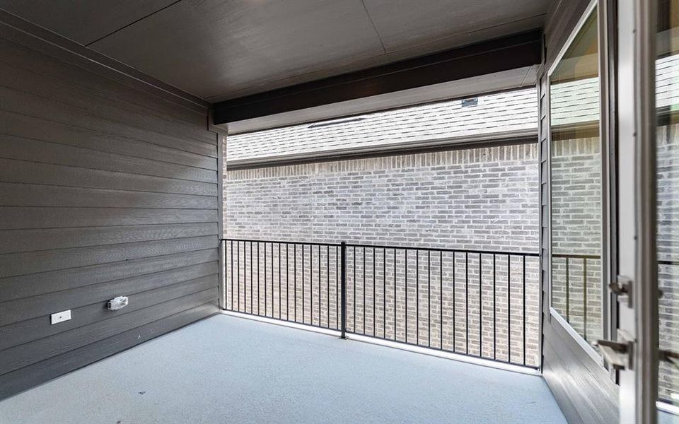 Covered outdoor balcony featuring horizontal plank siding, a concrete floor, and a black metal railing
