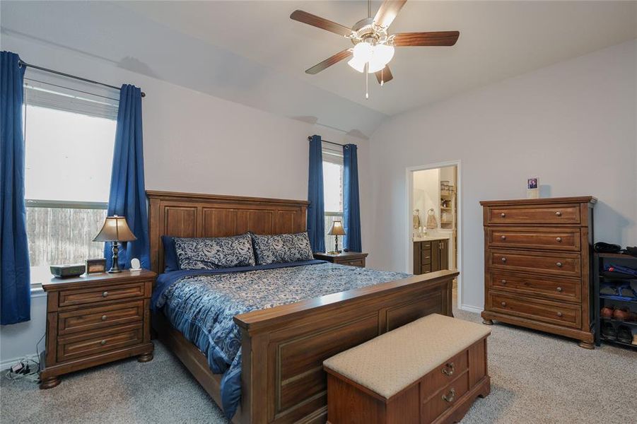 Bedroom featuring ensuite bathroom, ceiling fan, light colored carpet, and lofted ceiling