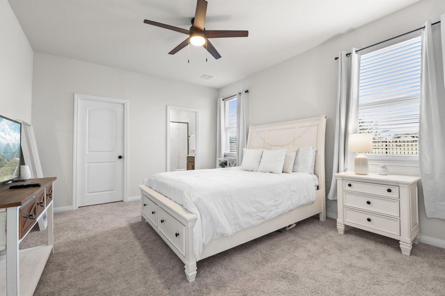 Bedroom featuring light carpet, ensuite bath, and ceiling fan Bedroom featuring light carpet, ensuite bath, and ceiling fan