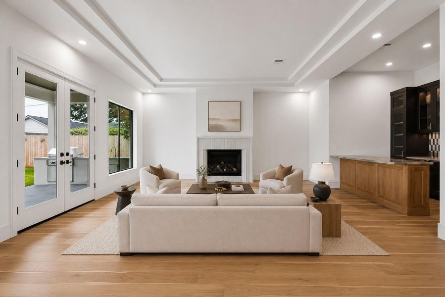 Gather around the fireplace or open the doors to the covered patio for effortless indoor outdoor living. Soaring tray ceilings, expansive windows, and a seamless connection to the kitchen and wet bar make this the heart of the home. **Virtually staged**