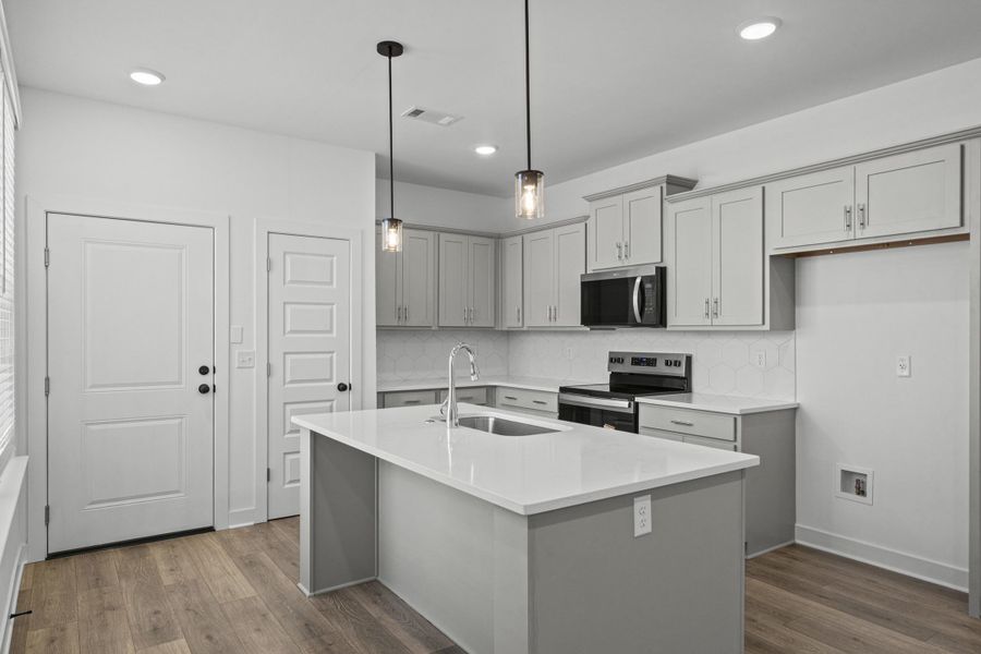 Modern kitchen featuring light gray cabinetry, white countertops, wood-finish flooring, and recessed lighting