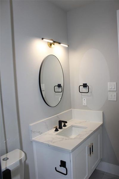 Bathroom with toilet, vanity, and tile patterned floors