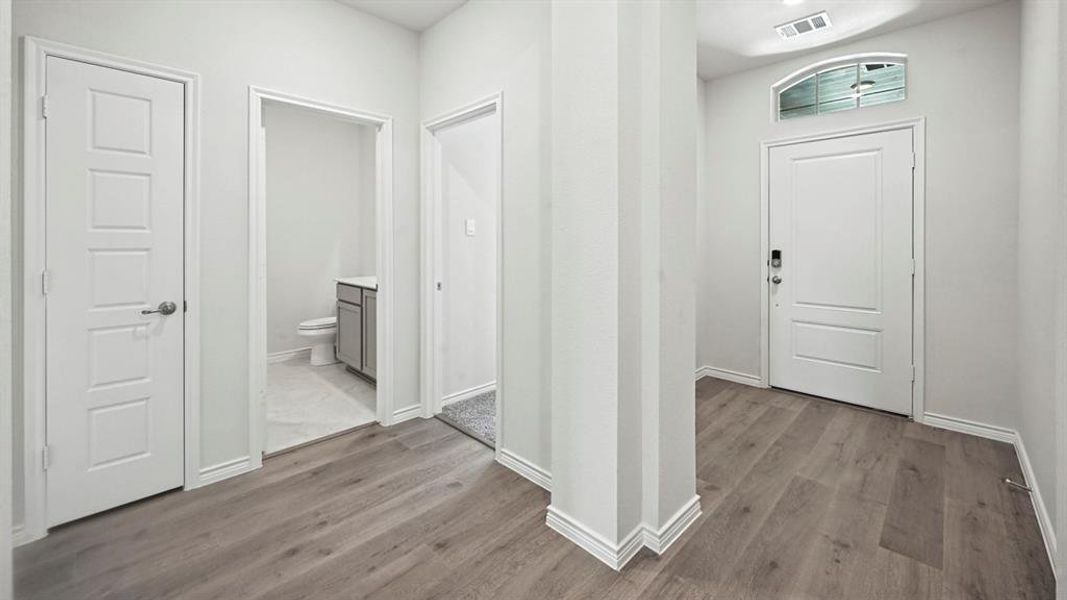 Entryway featuring wood-finish flooring, a white paneled door with an arched transom window, and white baseboards