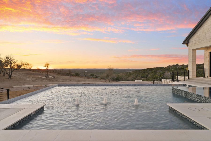Swimming pool with a patio with sunset views.