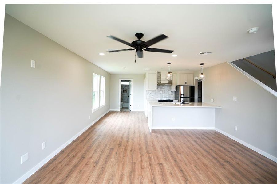Unfurnished living room featuring light wood-style floors, ceiling fan, and recessed lighting