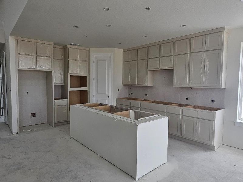 Kitchen with a center island and unfinished concrete flooring Kitchen with a center island and unfinished concrete flooring