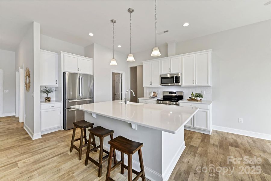 Kitchen features quartz counters, island with seating/storage, stainless steel appliances, tile back splash, upgraded lighting & breakfast area!