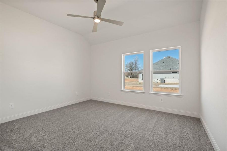 Unfurnished room featuring vaulted ceiling, ceiling fan, carpet, and baseboards