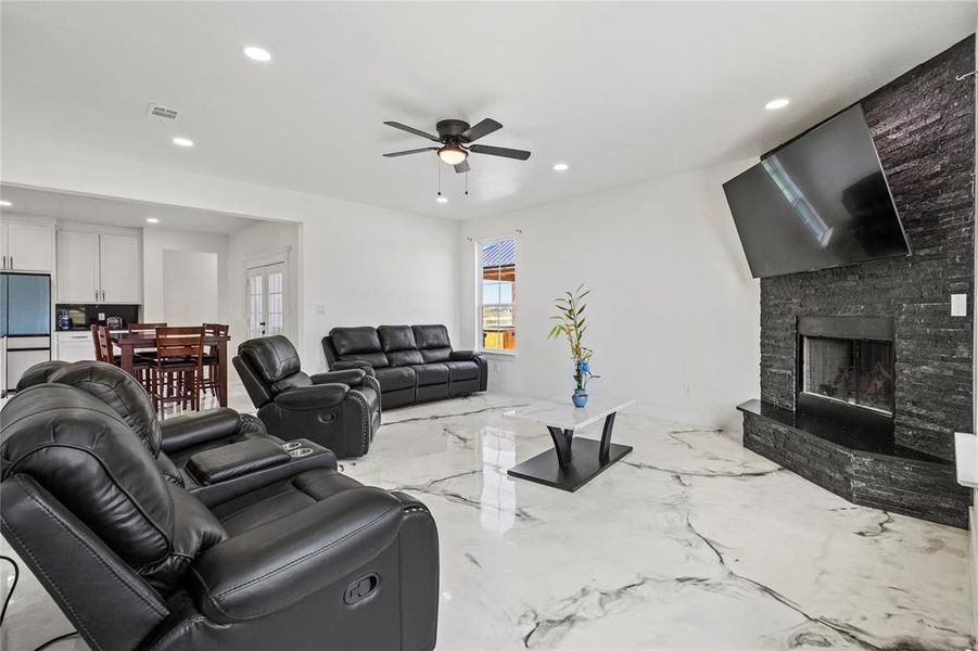 Living room with recessed lighting, a fireplace, marble tiled floors, and a ceiling fan Living room with recessed lighting, a fireplace, marble tiled floors, and a ceiling fan