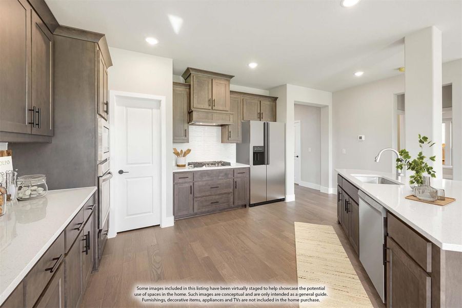 Kitchen with dark gray cabinets, white quartz countertops, stainless steel appliances, and hardwood floors