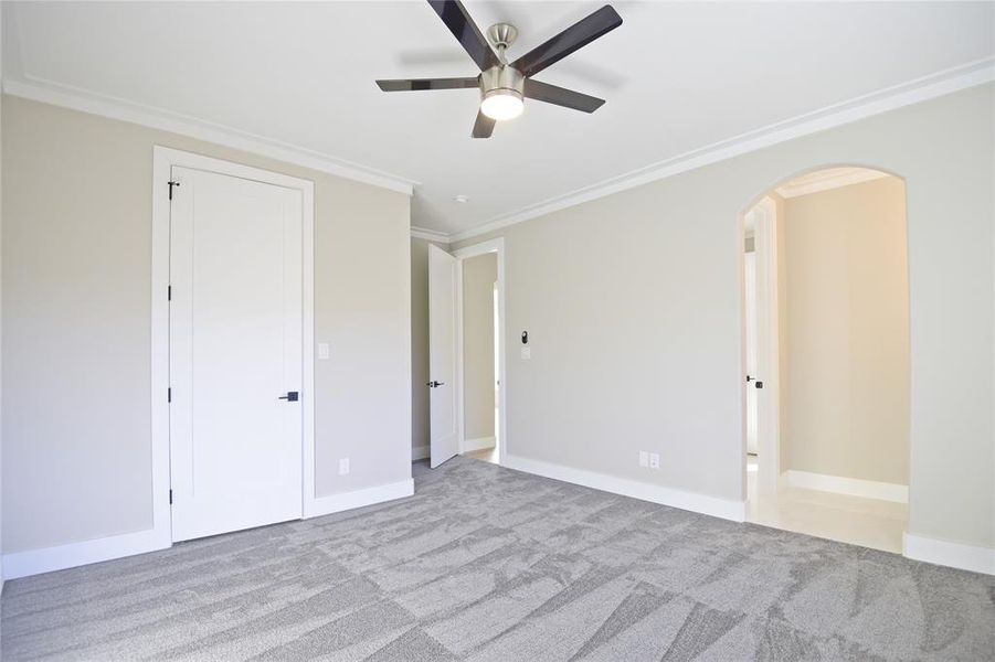 Unfurnished bedroom featuring ceiling fan, crown molding, and light colored carpet