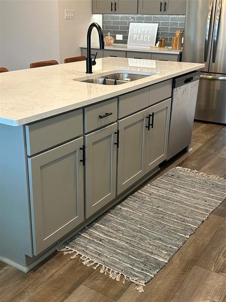 Kitchen with gray cabinets, dark wood finished floors, tasteful backsplash, and fridge Kitchen with gray cabinets, dark wood finished floors, tasteful backsplash, and fridge