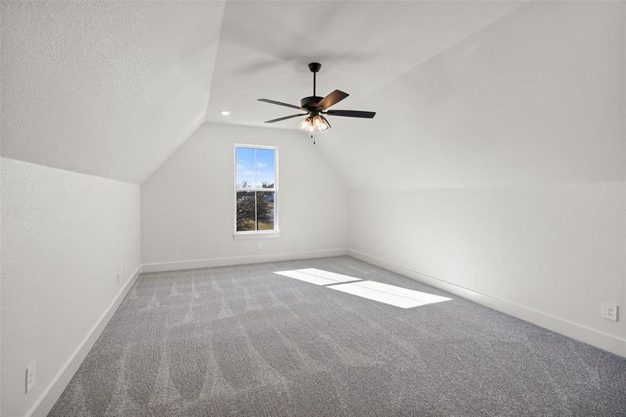 Bonus room with ceiling fan, carpet floors, a textured ceiling, and vaulted ceiling