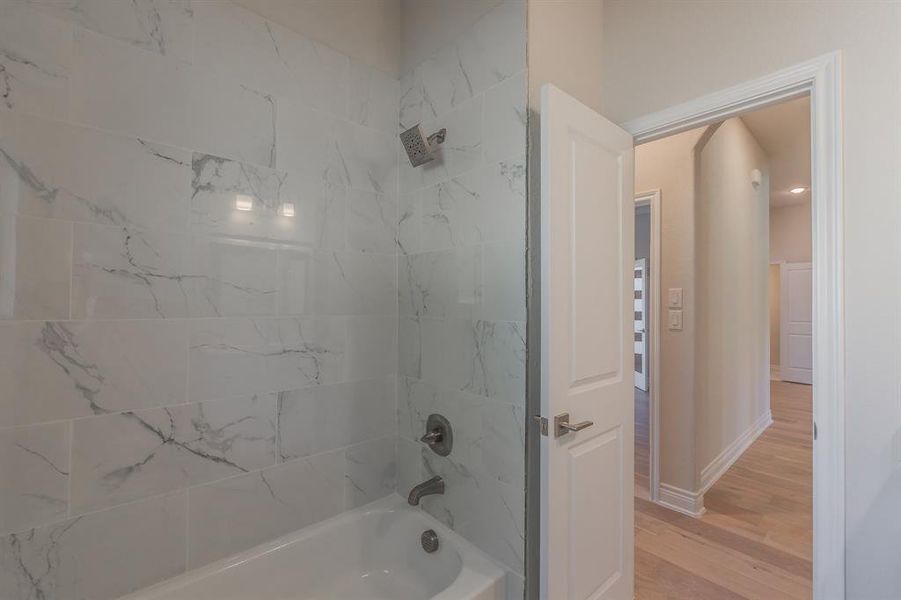 Bathroom featuring hardwood / wood-style floors and tiled shower / bath