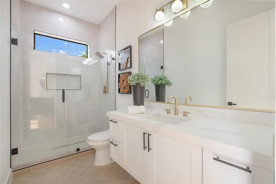 Bathroom featuring tile patterned flooring, vanity, toilet, and walk in shower