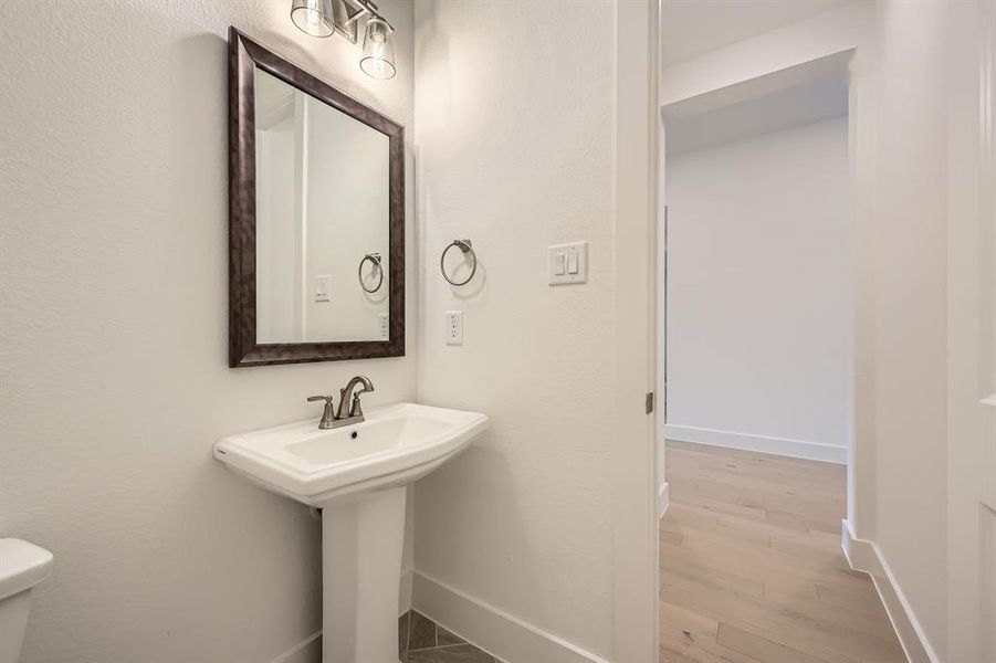 Half bath with baseboards, wood finished floors, toilet, and a sink