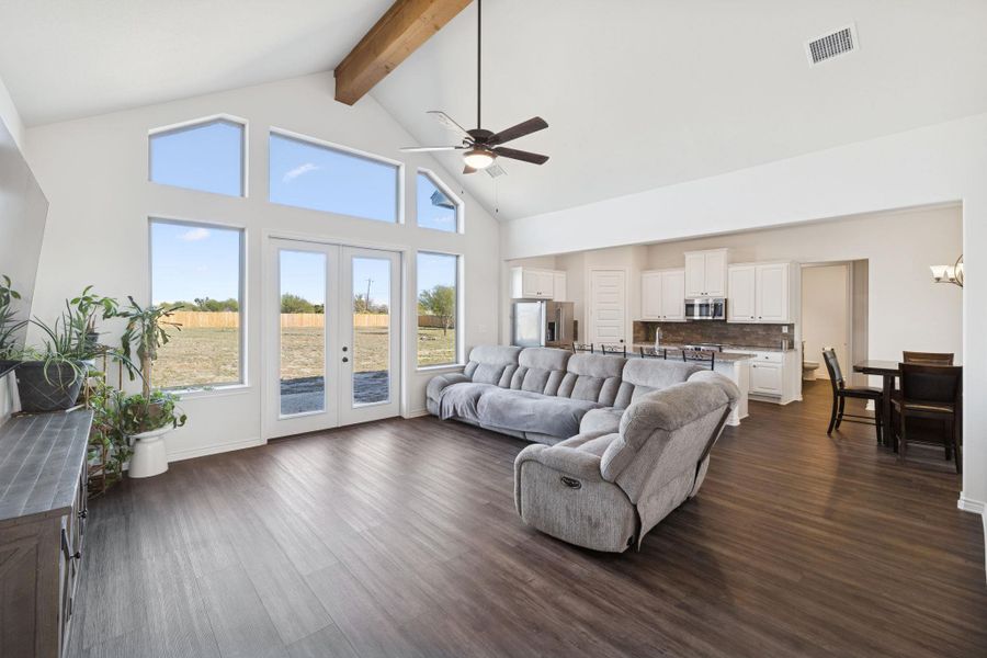 Living room with high vaulted ceiling, french doors, dark wood-style flooring, ceiling fan, and beam ceiling Living room with high vaulted ceiling, french doors, dark wood-style flooring, ceiling fan, and beam ceiling