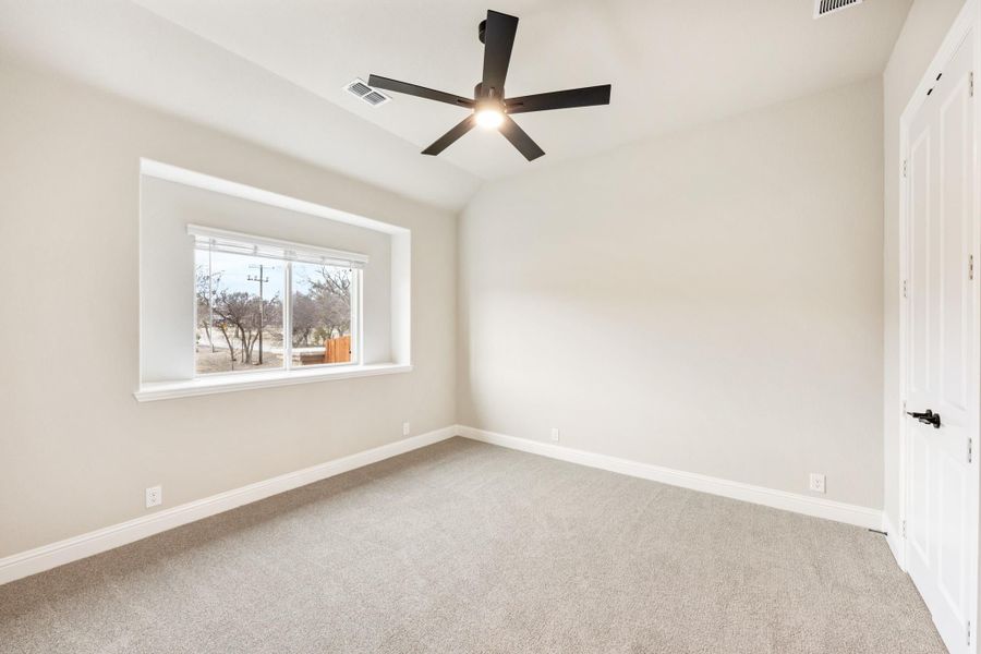 Empty bedroom with carpet flooring, black ceiling fan, and a single window with natural light Empty bedroom with carpet flooring, black ceiling fan, and a single window with natural light