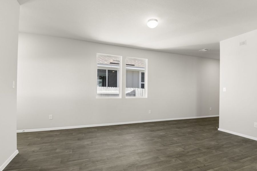 Image of a living room with dark vinyl flooring with light grey walls and two windows