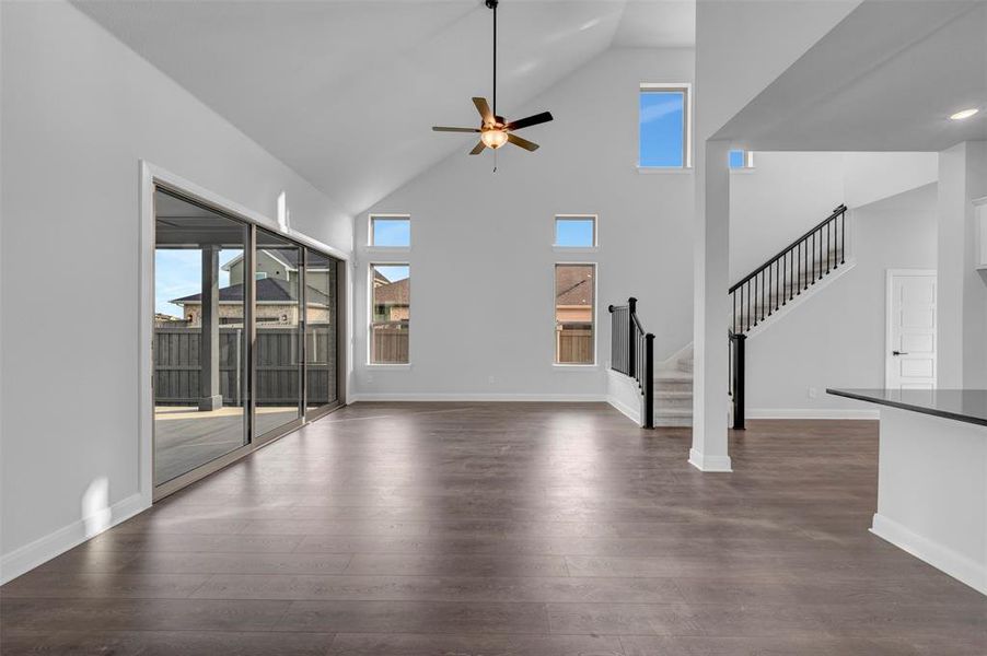 Unfurnished living room featuring a ceiling fan, dark wood-style flooring, and lofted ceiling Unfurnished living room featuring a ceiling fan, dark wood-style flooring, and lofted ceiling