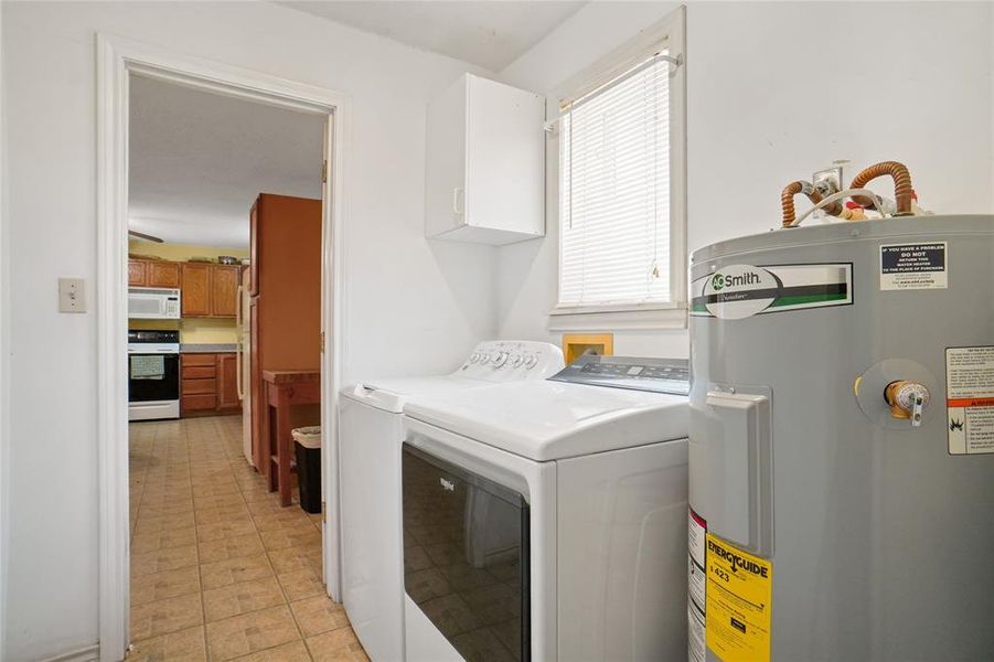 Laundry area featuring electric water heater, washer and clothes dryer hookups only, cabinet space, and light flooring