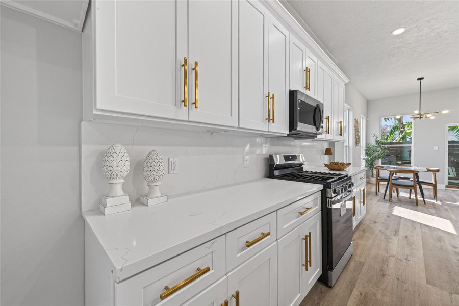 Chef-inspired kitchen featuring custom white shaker cabinetry with soft-close drawers, brushed gold hardware, and a full quartz backsplash for a clean, cohesive luxury finish.