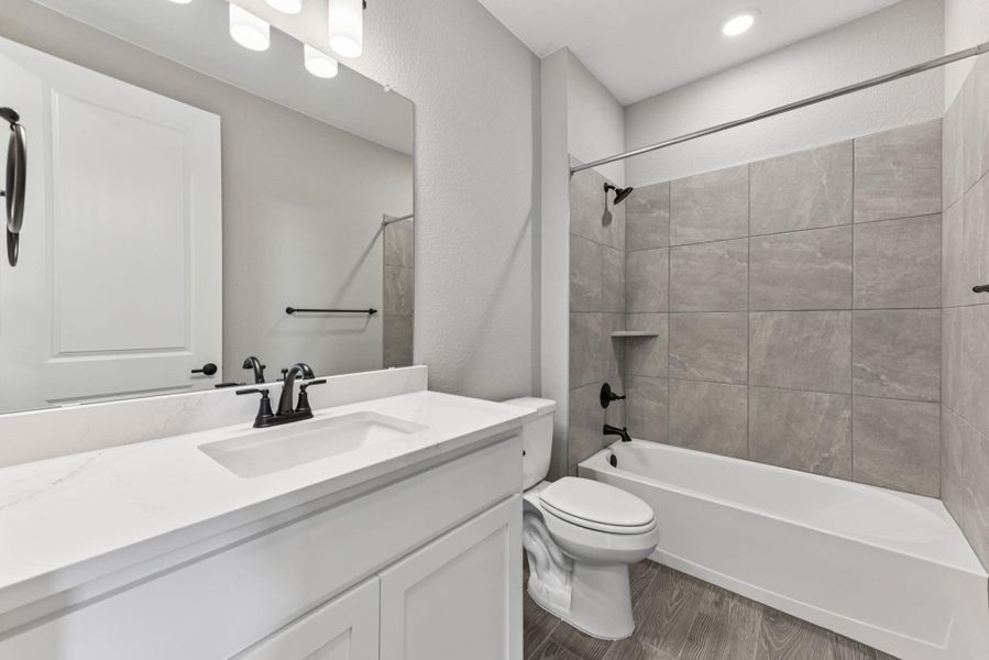 Bathroom featuring dark wood finished floors, vanity, and shower / bath combination Bathroom featuring dark wood finished floors, vanity, and shower / bath combination