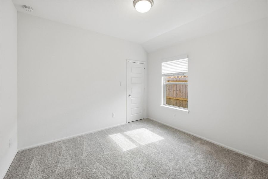 Bright and inviting room with plush carpeting, a large window for natural light, and a modern ceiling light fixture.