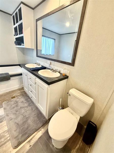 Bathroom featuring double vanity, light wood-style floors, and a bath