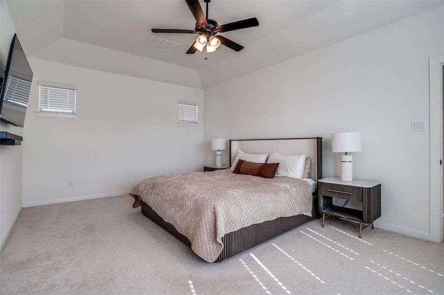 Bedroom featuring ceiling fan, light carpet, and a raised ceiling