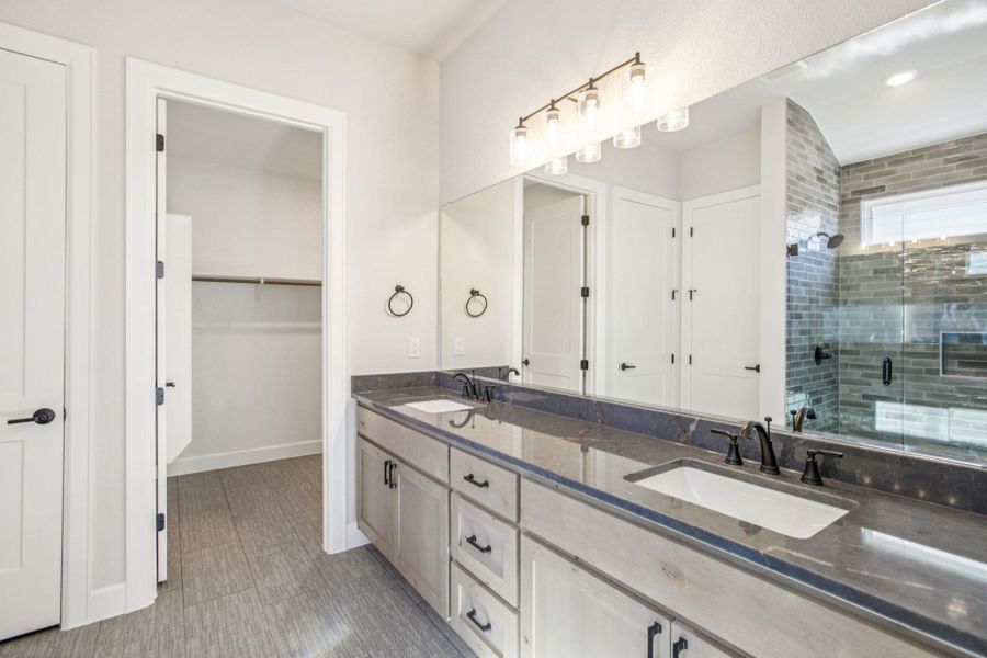 Full bath featuring double vanity, a shower stall, and a walk in closet Full bath featuring double vanity, a shower stall, and a walk in closet
