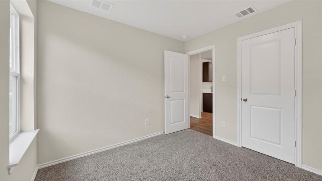 Room featuring neutral-toned walls, grey carpet flooring, and white trim