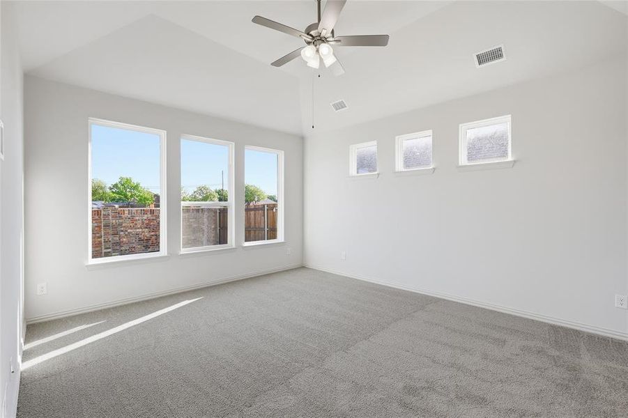 Empty room with ceiling fan, carpet flooring, and lofted ceiling Empty room with ceiling fan, carpet flooring, and lofted ceiling