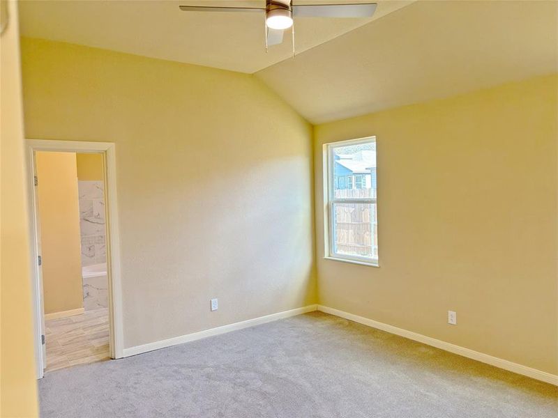 Empty room with vaulted ceiling, carpet flooring, and a ceiling fan