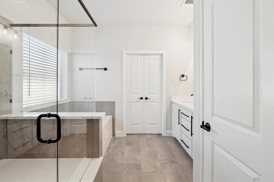 Full bathroom with a garden tub, a shower stall, vanity, and baseboards