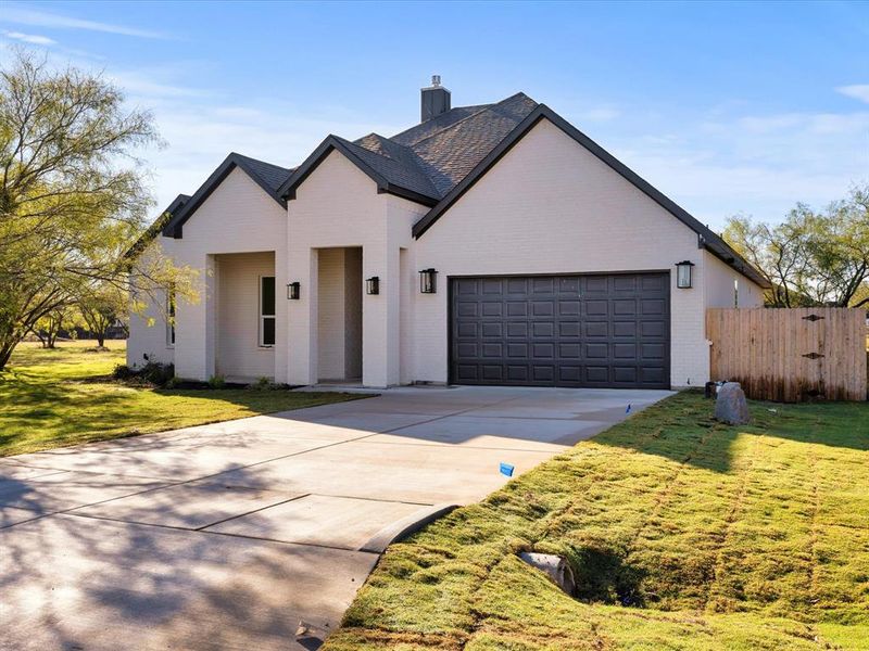 View of front of home featuring brick siding, driveway, an attached garage, a gate, and a chimney