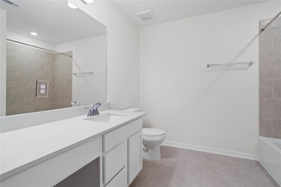 Secondary bath features tile flooring, bath/shower combo with tile surround, stained wood cabinets, beautiful light countertops, mirror, sleek fixtures and modern finishes!