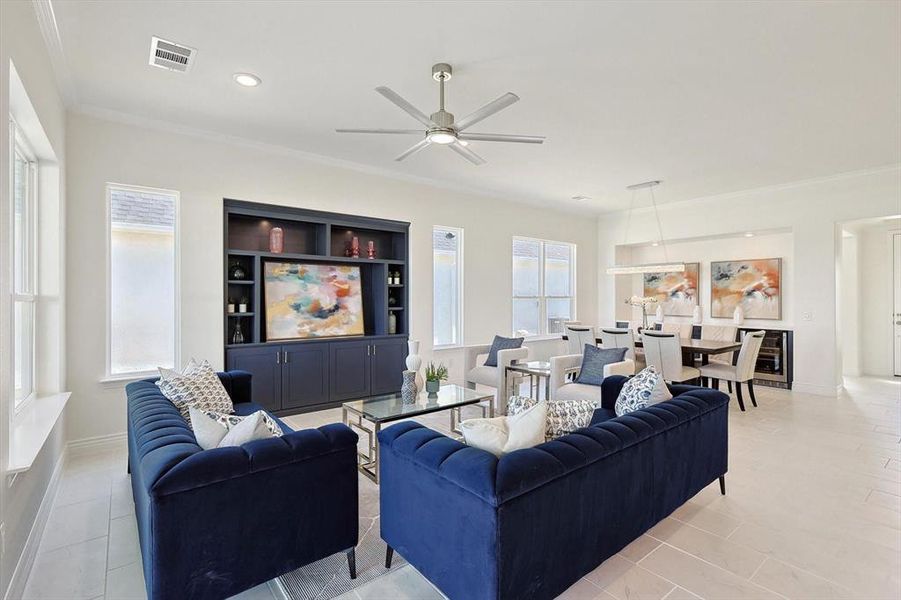 Living room with ceiling fan, light tile flooring, and ornamental molding