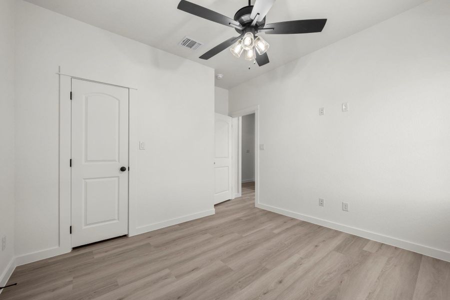 A quiet bedroom retreat with wood-look flooring and a modern ceiling fan for year-round comfort. A quiet bedroom retreat with wood-look flooring and a modern ceiling fan for year-round comfort.