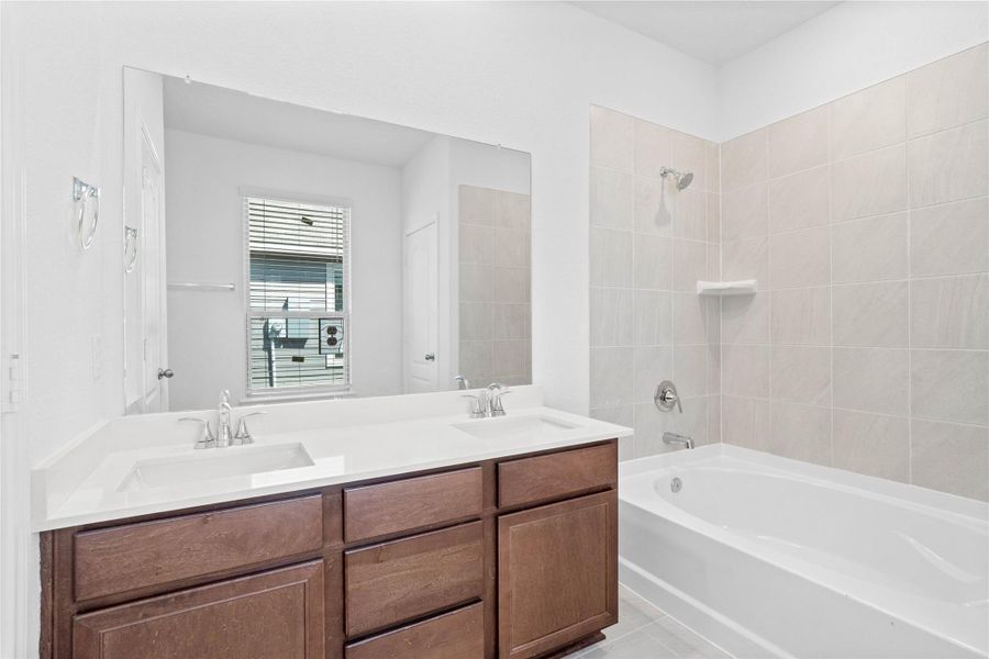 This stunningly updated primary bathroom is truly move-in ready! It features stained cabinetry with light countertops, dual sinks, a large mirror, high ceilings, custom paint, and sleek modern finishes throughout.