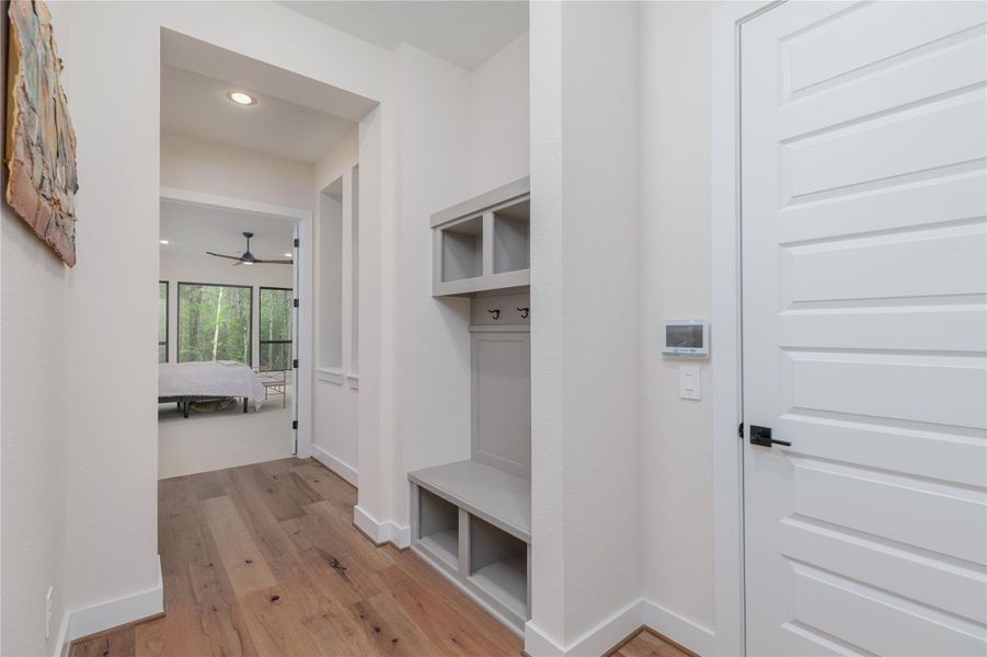 To the right of the property is the luxurious primary suite accessed through this private walkway.  A built-in mud area conveniently positioned next to the garage entry door.