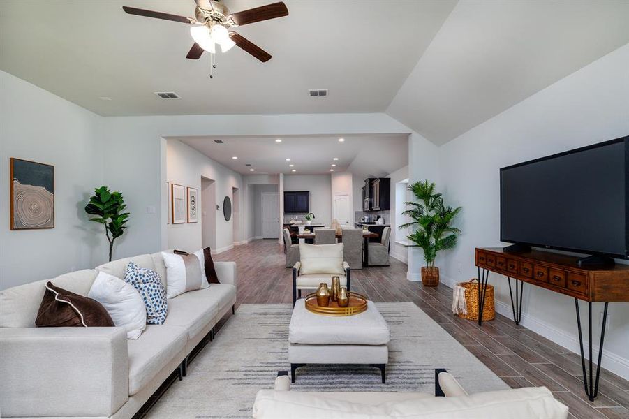 Living room with wood finish floors, ceiling fan, vaulted ceiling, and recessed lighting