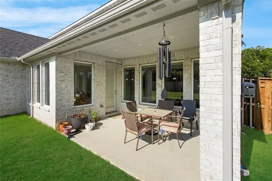 Covered patio featuring a concrete surface, white brick exterior, and multiple large windows
