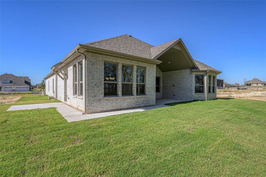 Back of property with brick siding, a lawn, roof with shingles, and a patio area Back of property with brick siding, a lawn, roof with shingles, and a patio area