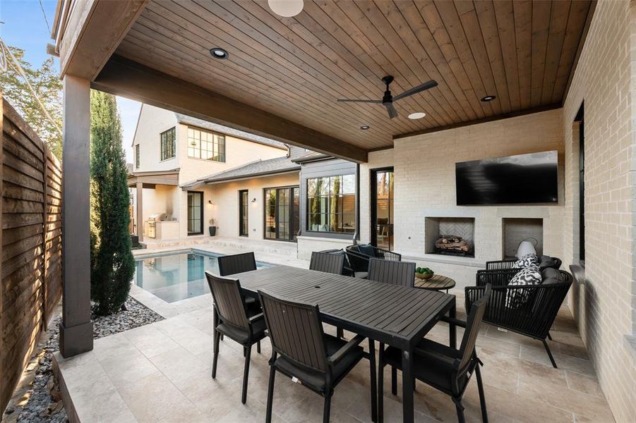 View of patio / terrace with ceiling fan, an outdoor pool, outdoor dining space, and an outdoor brick fireplace