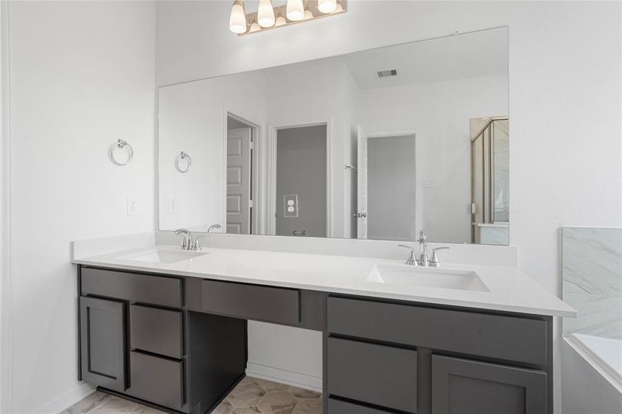 This primary bathroom is definitely move-in ready! Featuring an oversized framed walk-in shower with tile surround, separate garden tub for soaking after a long day with custom tile detailing, stained cabinets with light countertops, dual vanities, high ceilings, neutral paint, sleek and modern finishes.