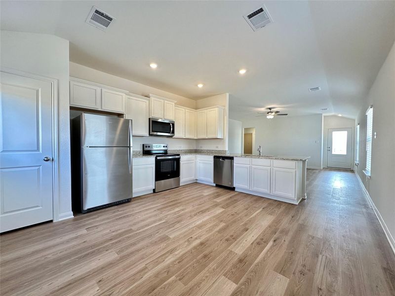 Kitchen includes granite countertops, luxury vinyl plank flooring, 36” upper cabinets with crown molding, a full suite of stainless-steel Whirlpool appliances – including refrigerator with ice maker.