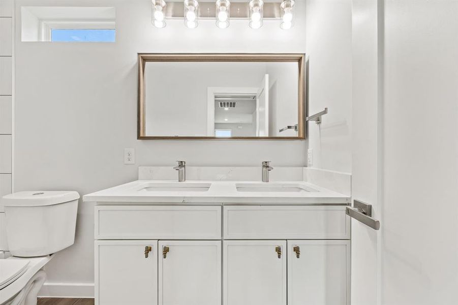 Bathroom featuring hardwood / wood-style floors, toilet, and dual bowl vanity